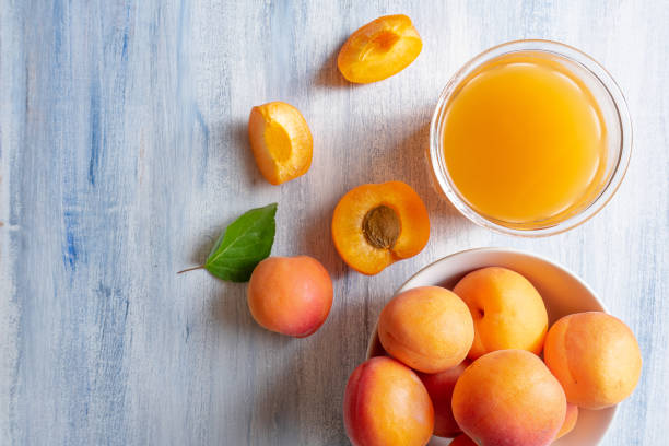 ripe apricots and glass of apricot juice on blue rustic background with copy space. selective focus. eco food concept. fresh summer drinks. detox. non alcoholic. horizontal. top view - peach juice imagens e fotografias de stock