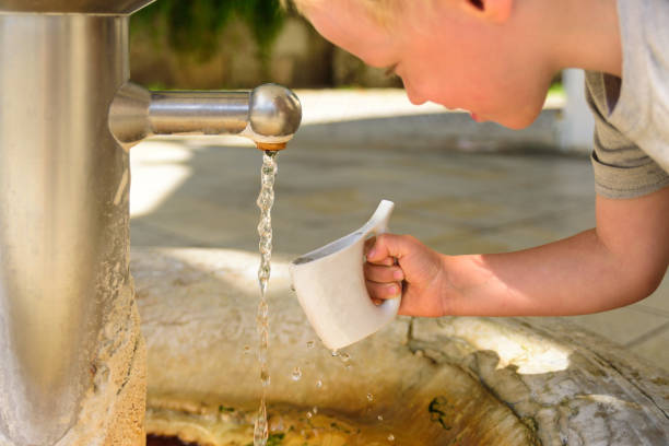 Little boy catching a water from hot mineral spring in Karlovy Vary in special mug