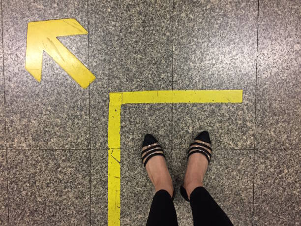 道路上の足と矢。矢印方向の黄色の記号と床に立っています。トップビュー。 - choice teenager footpath arrow sign ストックフォトと画像