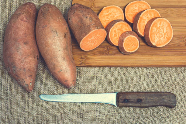 istock Sliced raw sweet potatoes on a wooden cutting board 1164273384
