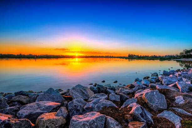 Cold Lake sunset photographed in the summer from the Provincial Park in Cold Lake Alberta.  3 Photo stitch was taken with a tilt shift lens to create front to back sharp focus and extreme wide view of the beach.  Great copy space in the sky and water.