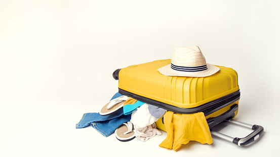 hat on a yellow suitcase with things of the traveler on a white background. banner. Travel and adventure concept