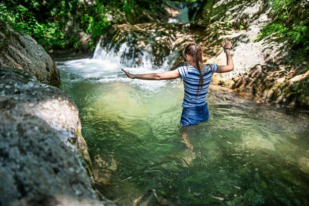 teenage girl walking into cold mountain stream - wading imagens e fotografias de stock