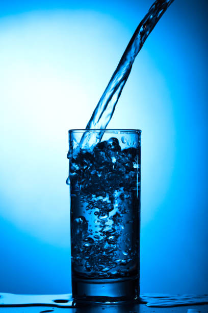 istock Pure water with bubbles pours into the glass on a blue background 1164288662