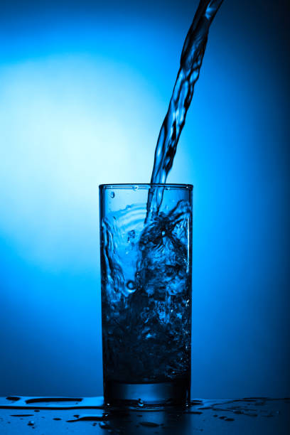 istock Fresh water with bubbles pours into the glass on a blue background 1164288680