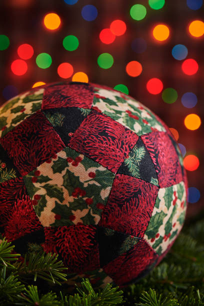 christmas decoration ball sewn from pieces of fabrics on branches of spruce, dark colorful bokeh background - christmas quilt craft patchwork imagens e fotografias de stock