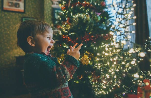 bambino che gioca con le luci di natale a casa - christmas child foto e immagini stock