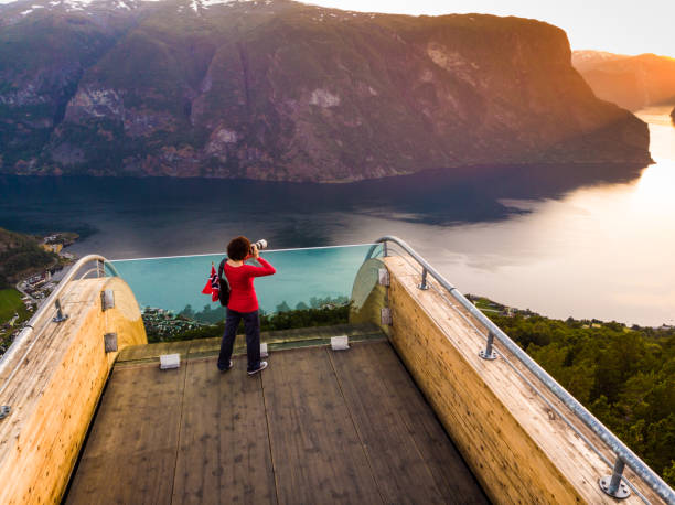 Tourist enjoying fjord view on Stegastein viewpoint Norway Aerial view. Tourist woman with norwegian flag and photo camera enjoying fjord Aurlandsfjord view from Stegastein viewing point. National tourist route Aurlandsfjellet, Norway stegastein viewpoint stock pictures, royalty-free photos & images