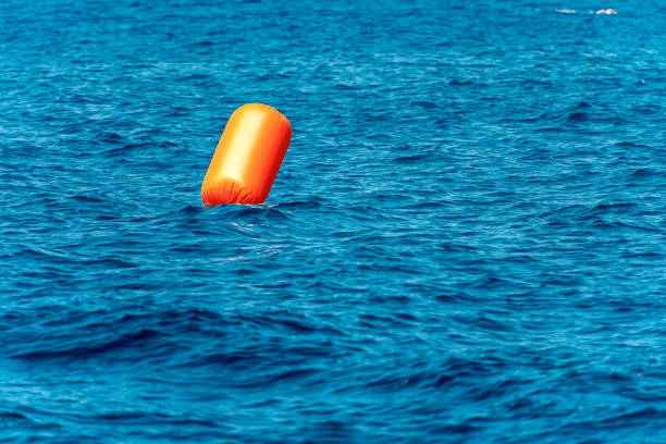 большой оранжевый надувной сигнал буй в море - buoy anchored sea wave стоковые фото и изображения