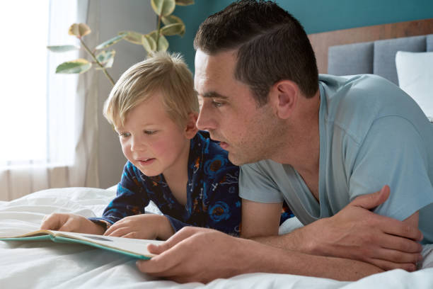 istock father and son lying in bed reading 1164293010