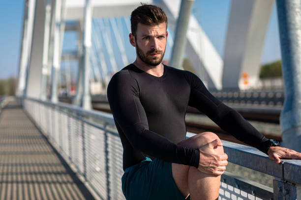 istock Young man stretching his muscles before before running on the bridge in the city. 1164293479
