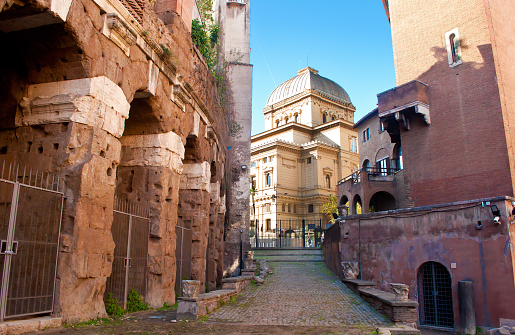 View of Tempio Maggiore di Roma between the walls of Casina of Vallati and columns and ruins of Teatro Marcello in the old town of Rome, Italy. Cloudless autumn day