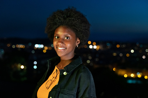 Cool young girl in casual clothes with city lights at background