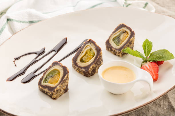 istock Dessert Maki Sushi Chocolate Roll with Various Fruit and Cream Cheese and sauce on white plate 1164303573