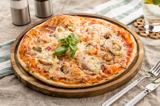 Pizza with seafood, mozzarella, mussels, octopus, squid, salmon, shrimp serves on the table Pizza with seafood, mozzarella, mussels, octopus, squid, salmon, shrimp serves on the table studio shot fish pie stock pictures, royalty-free photos & images