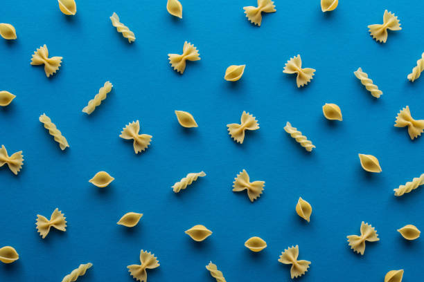 top view of different uncooked pasta on blue background - pasta directly above fusilli food imagens e fotografias de stock