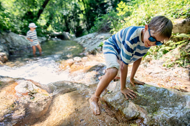 istock Two little hikers playing in cold mountain stream 1164307995