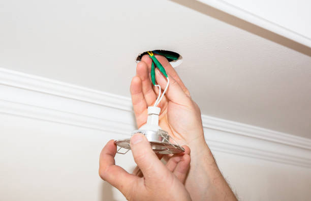 istock Man is installing electrical light bulb in the ceiling. Maintenance repair works in the flat. Restoration indoors. 1164308237