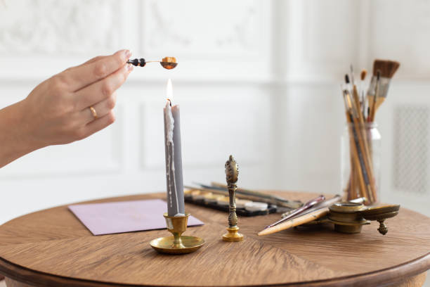 istock A calligrapher woman makes a wax seal on the envelope. Close-up. Soft focus. 1164309430