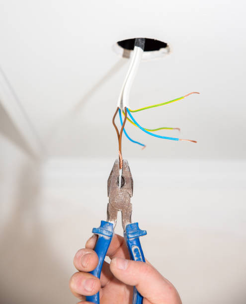 istock Man is holding pliers in his hands. Electrical insulator for light bulb. Adhesive tape for maintenance repair works in the flat. Restoration indoors. 1164309457