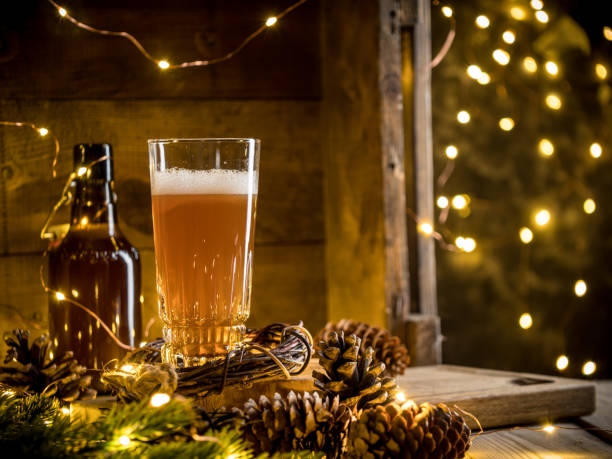 Beer in glass on wooden background with Christmas lights and pine cones stock photo