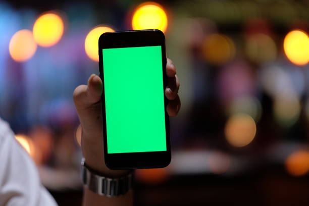 close up one hand holding a green screen smartphone