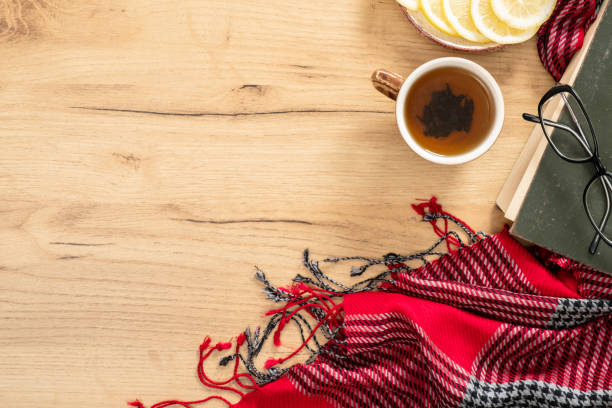 Book, knitted red scarf, cup of tea and lemon on wooden table. Flat lay, top view, copy space. Hygge autumn concept. Book, knitted red scarf, cup of tea and lemon on wooden table. Flat lay, top view, copy space. Hygge autumn concept. hygge photos stock pictures, royalty-free photos & images