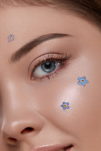 istock romantic woman's eye looking to the camera with fresh blue flowers on cheek 1164320851