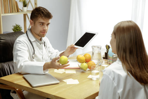 istock Smiling nutritionist showing a healthy diet plan to patient 1164323159