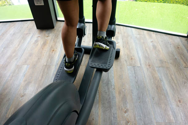 istock Female legs using elliptical trainer in gym 1164324321
