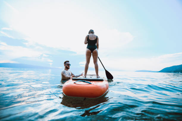 istock Male Holding Paddle Board To Balance It For Girlfriend 1164326111