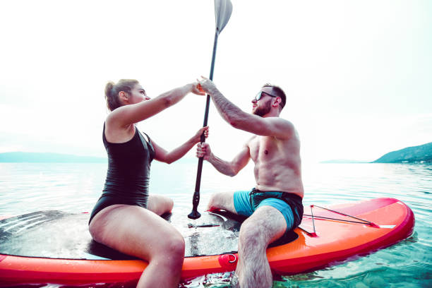 pareja luchando por el remo en paddleboard - paddleboard oar women lake fotografías e imágenes de stock