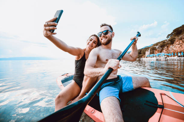 coppia che si fa selfie mentre pagaia sul lago - lake summer beach nautical vessel foto e immagini stock