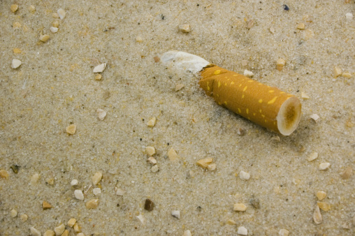 Smoked Cigarette half buried in Sand