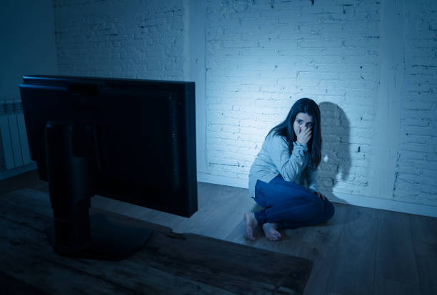 istock Dramatic portrait of sad scared young woman on the ground staring a computer suffering cyberbullying and harassment. Being online abused by stalker feeling desperate. Dangers of internet concept. 1164330525