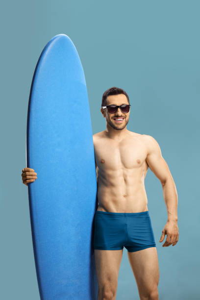 istock Young muscular guy holding a surfing board 1164332560