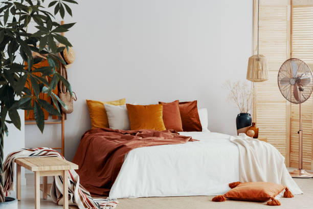 istock Autumn colored pillows on king size bed in chic bedroom interior 1164337857
