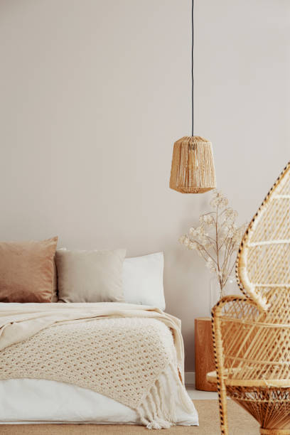 istock Peacock chair, wicker chandelier and cozy bed, copy space on empty wall 1164337952