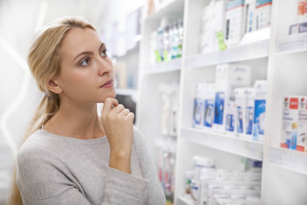 charming young woman shopping at pharmacy - choice thinking women decisions imagens e fotografias de stock