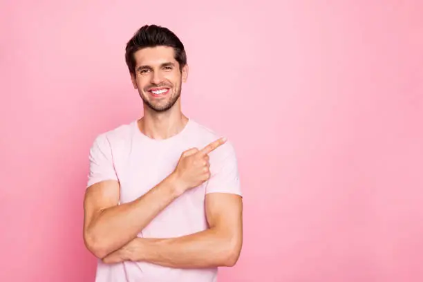 Portrait of his he nice attractive cheerful cheery confident content glad guy pointing, forefinger aside promotion surprise gift present advert ad isolated over pink pastel background