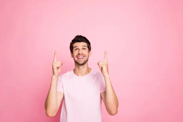 Portrait of his he nice attractive lovely cheerful cheery glad confident guy pointing two, forefingers up cool advert isolated over pink pastel background