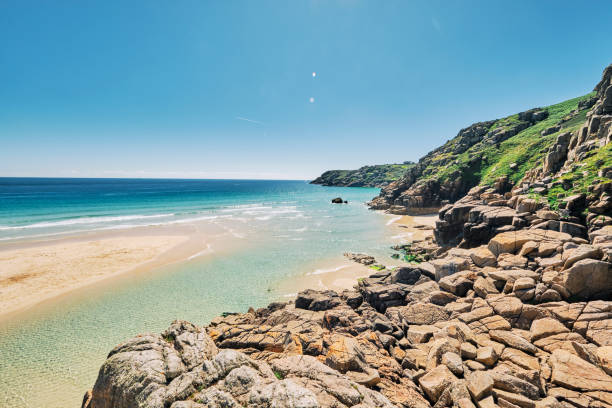 Views over the rugged rock formations from Pedn Vounder Beach towards Porthcurno, Cornwall on a bright sunny June day.