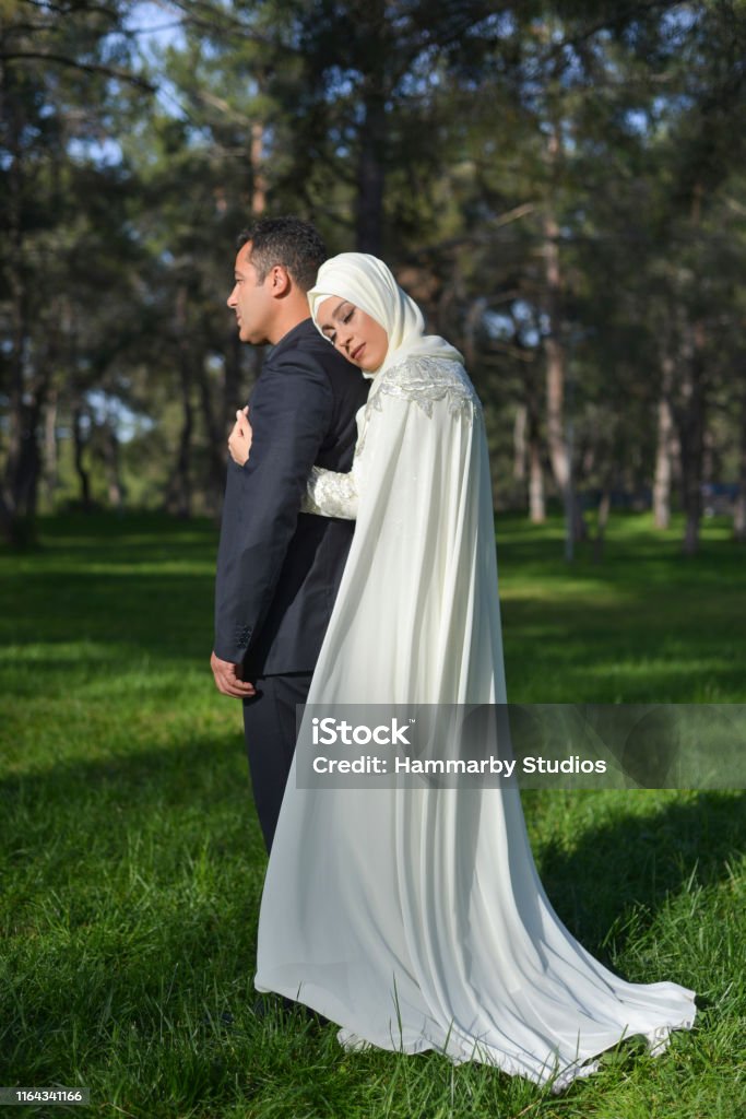 Portrait of Muslim bride and groom couple posing in a public park Portrait of Muslim bride and groom couple posing in a public park. Vertical shot. Islam Stock Photo