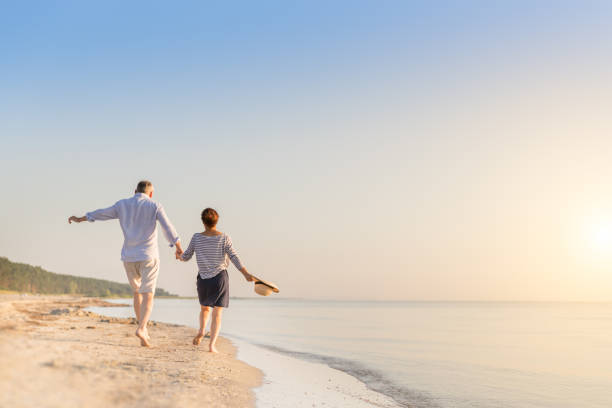 felice coppia senior in spiaggia - active holidays foto e immagini stock