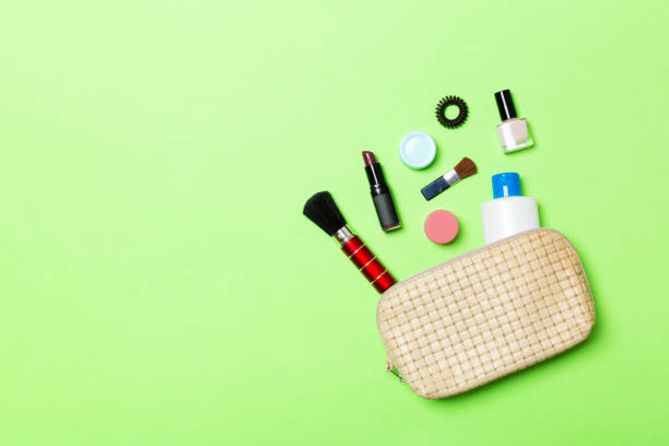 aerial view of a leather cosmetics bag with make up beauty products spilling out on green background. beautiful skin concept with copy space - pampering nail polish make up spilling imagens e fotografias de stock