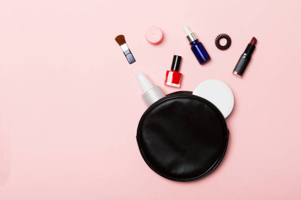 top view of set of make up and skin care products spilling out of cosmetics bag on pink background. beauty concept - pampering nail polish make up spilling imagens e fotografias de stock