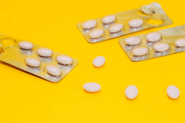 istock Different pills and vitamins are scattered on a yellow background, pills in a pack 1164344953