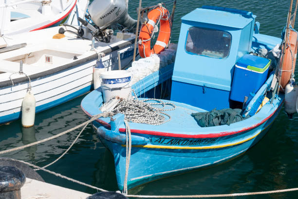 Chios, Greece - July 25, 2019: A sunny, hot midday in summer in the harbor of Agia Ermioni on the Greek Island of Chios in the Aegean Sea. A line of fishing boats are tied up to the quay.