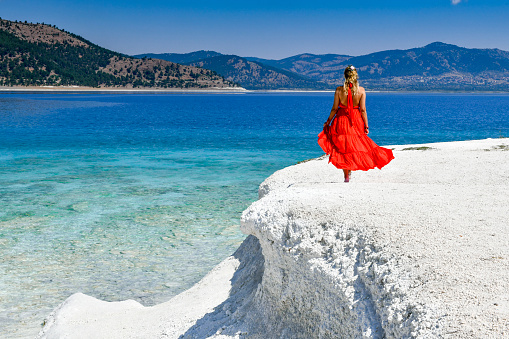 Woman in red dress walking on the beach.