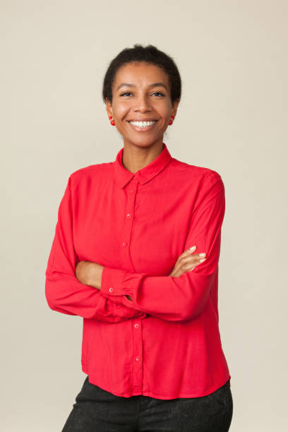 Studio portrait of an attractive 30 year old woman in a red shirt on a beige background stock photo
